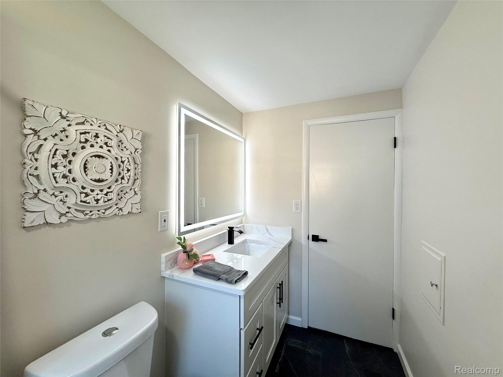 39909 Lynn Street Canton, MI 48187 - Photo 19 of 45 Contemporary bathroom featuring a vanity with a white countertop and integrated sink, matte black faucet, and modern cabinetry with dark hardware