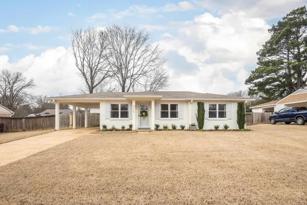 a front view of a house with a yard and trees