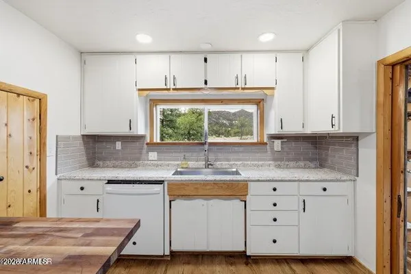 a kitchen with granite countertop white cabinets and window
