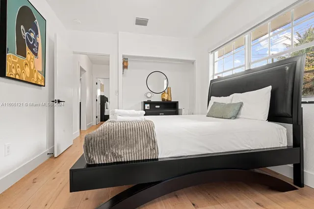 a bedroom with a bed and a large mirror on the dresser