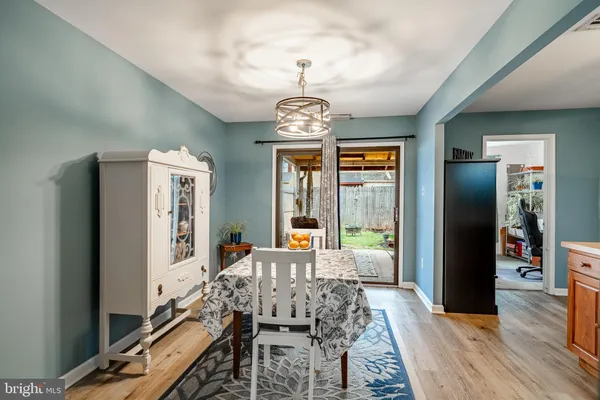 a living room with furniture dining table wooden floor and a chandelier