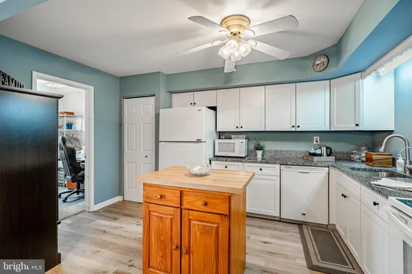 a kitchen with stainless steel appliances granite countertop a refrigerator a stove a sink and white cabinets
