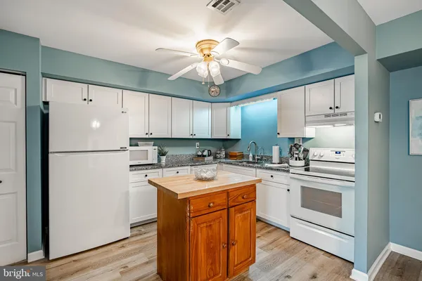 a kitchen with a white refrigerator a sink and a stove top oven