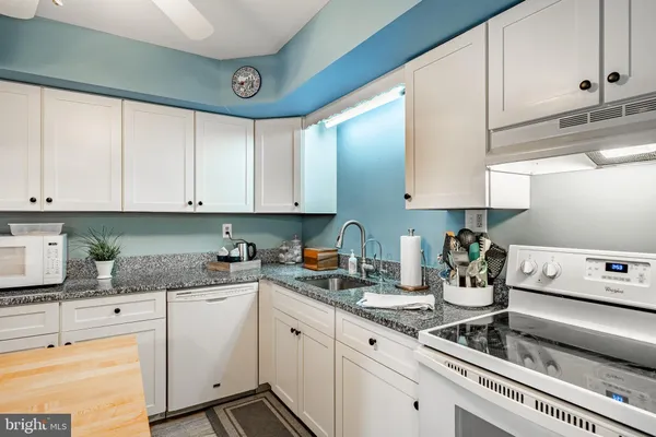 a kitchen with granite countertop white cabinets and white appliances