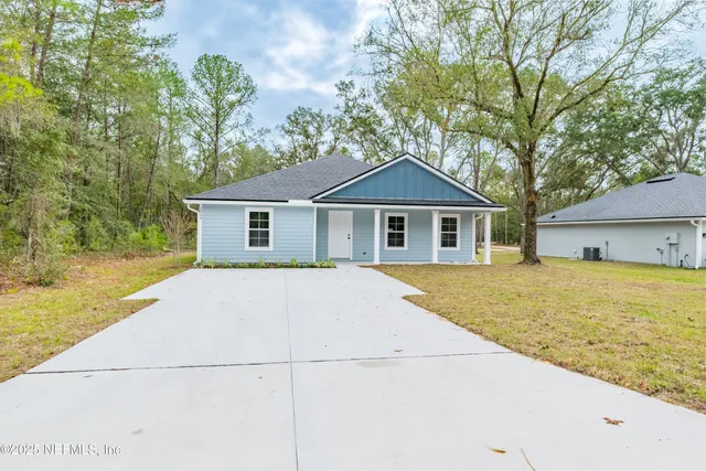 a front view of house with yard and trees in the background