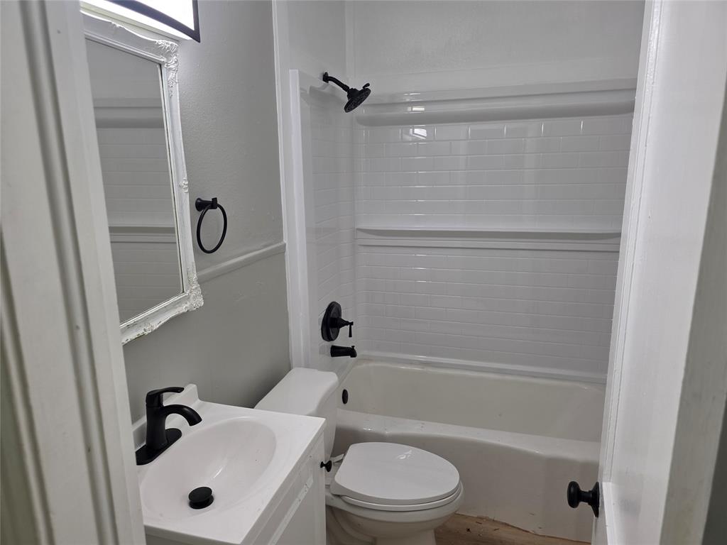 2804 Summer Avenue Waco, TX 76708 - Photo 7 of 13 Modern bathroom featuring a white vanity with integrated sink, matte black fixtures, a white framed mirror, and a white subway tile-patterned shower surround over a white bathtub