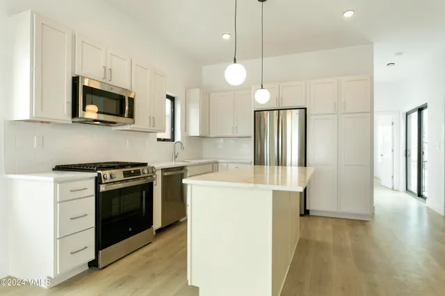 a kitchen with stainless steel appliances granite countertop a refrigerator a stove a microwave oven a sink with island and chairs