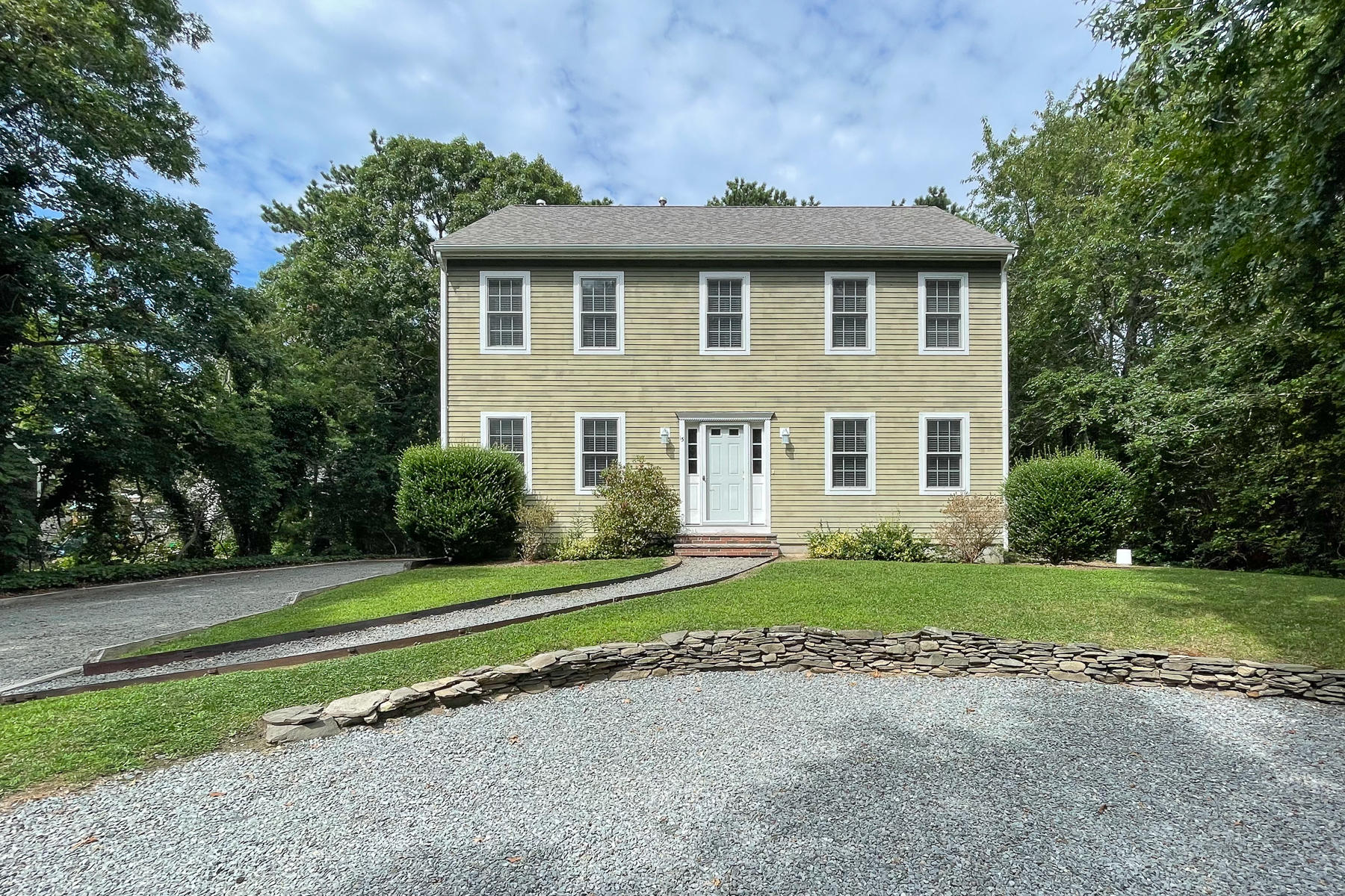 a front view of a house with a yard and trees
