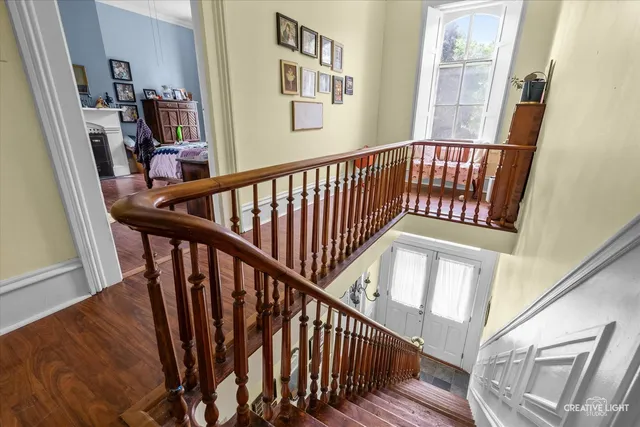 a view of staircase with lots of frames on wall and wooden floor