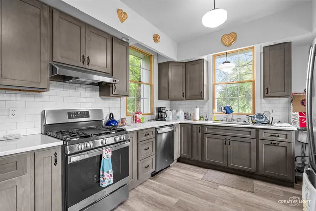 a kitchen with stainless steel appliances a stove a sink and a microwave