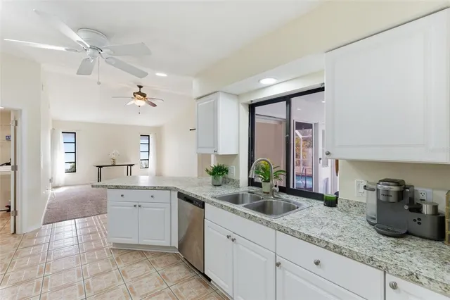 a kitchen with granite countertop a sink and white cabinets