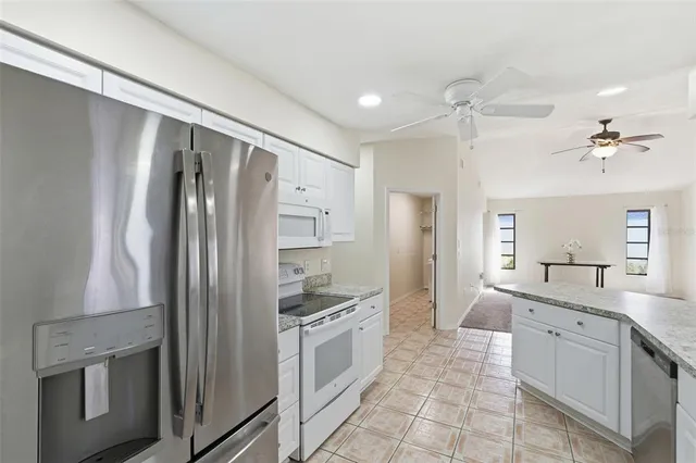 a large kitchen with a refrigerator a sink a stove and cabinets