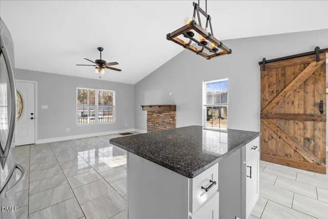 a kitchen with stainless steel appliances granite countertop a sink a stove a refrigerator and white cabinets