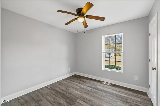 an empty room with a ceiling fan and wooden floor