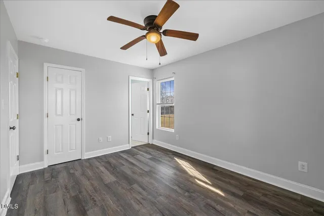 an empty room with wooden floor and ceiling fan