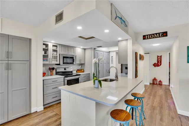 a kitchen with granite countertop a refrigerator a stove and white cabinets with wooden floor