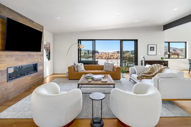 a living room with furniture a flat screen tv and a floor to ceiling window