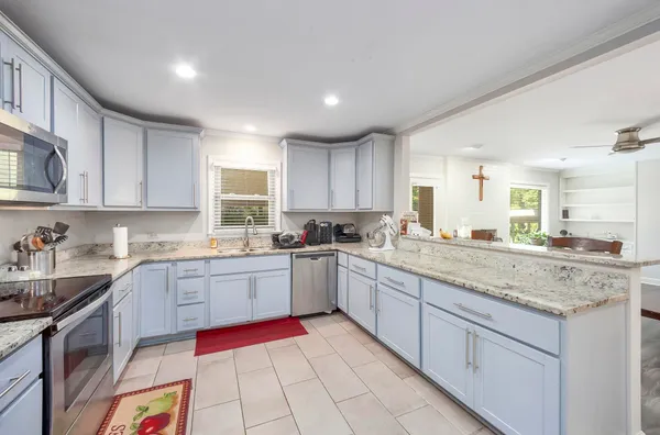 a kitchen with granite countertop stainless steel appliances sink stove and cabinets