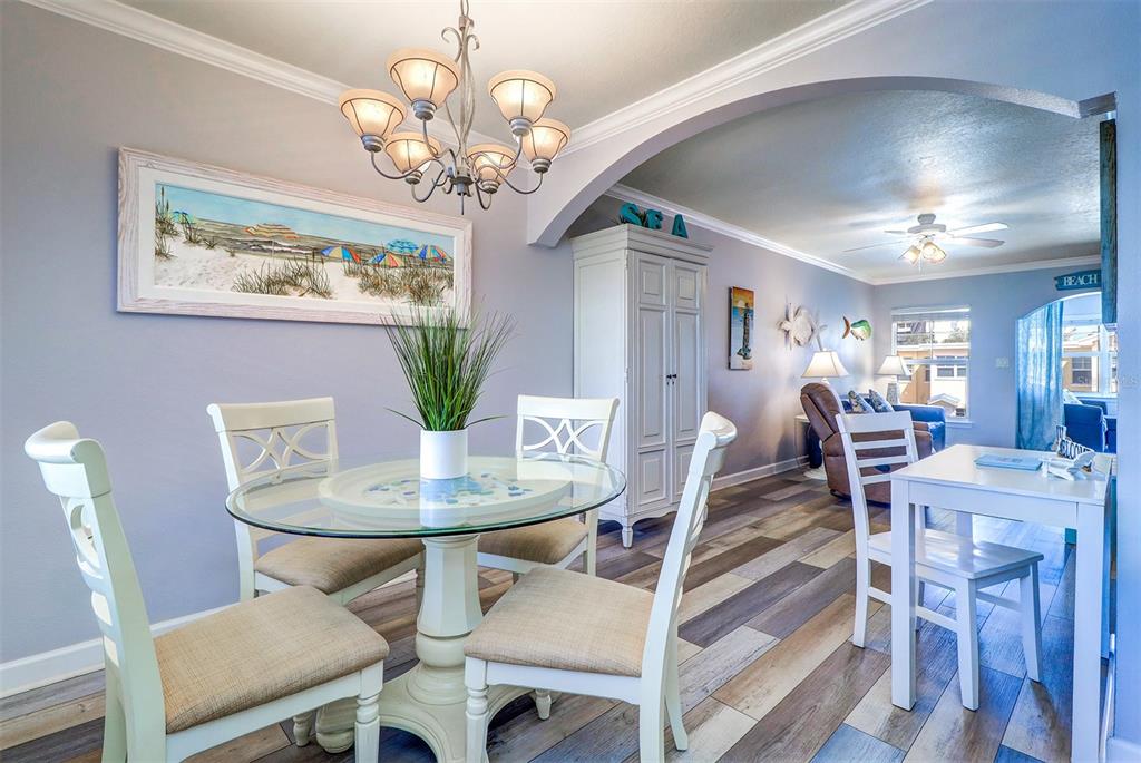 19417 Gulf Boulevard, Unit A202 Indian Shores, FL 33785 - Photo 12 of 35 a view of a dining room with furniture a chandelier and wooden floor