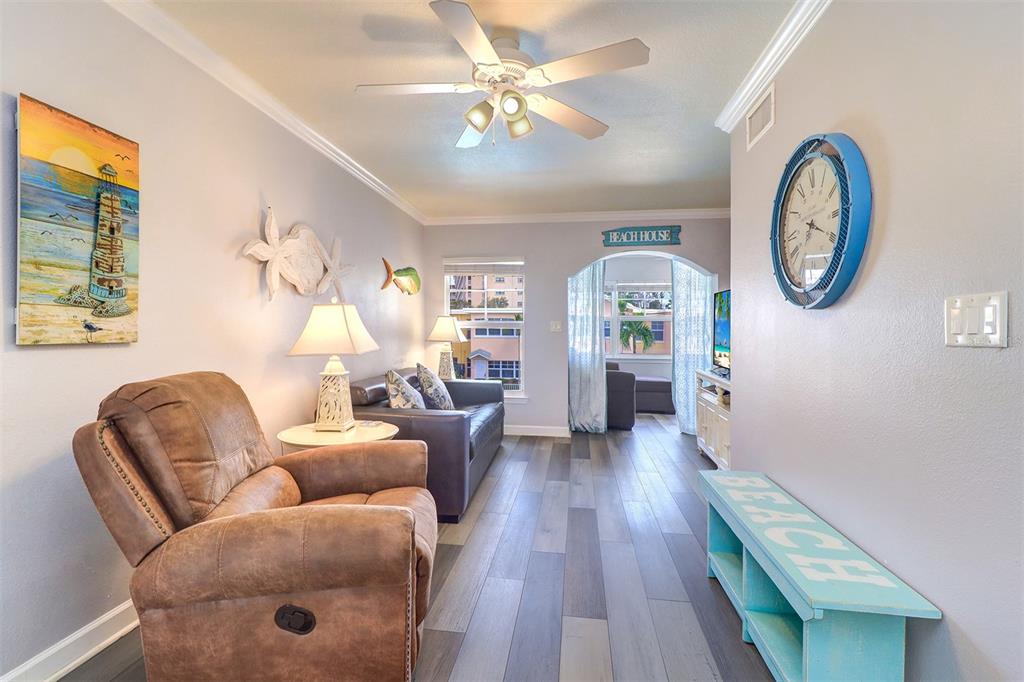 19417 Gulf Boulevard, Unit A202 Indian Shores, FL 33785 - Photo 16 of 35 a living room with furniture a chandelier fan and a window