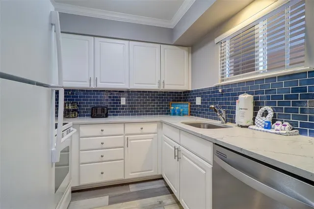 a kitchen with white cabinets and sink