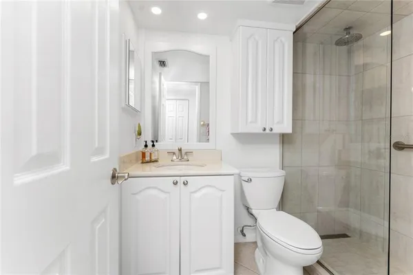 a bathroom with a toilet a sink a mirror a vanity and shower