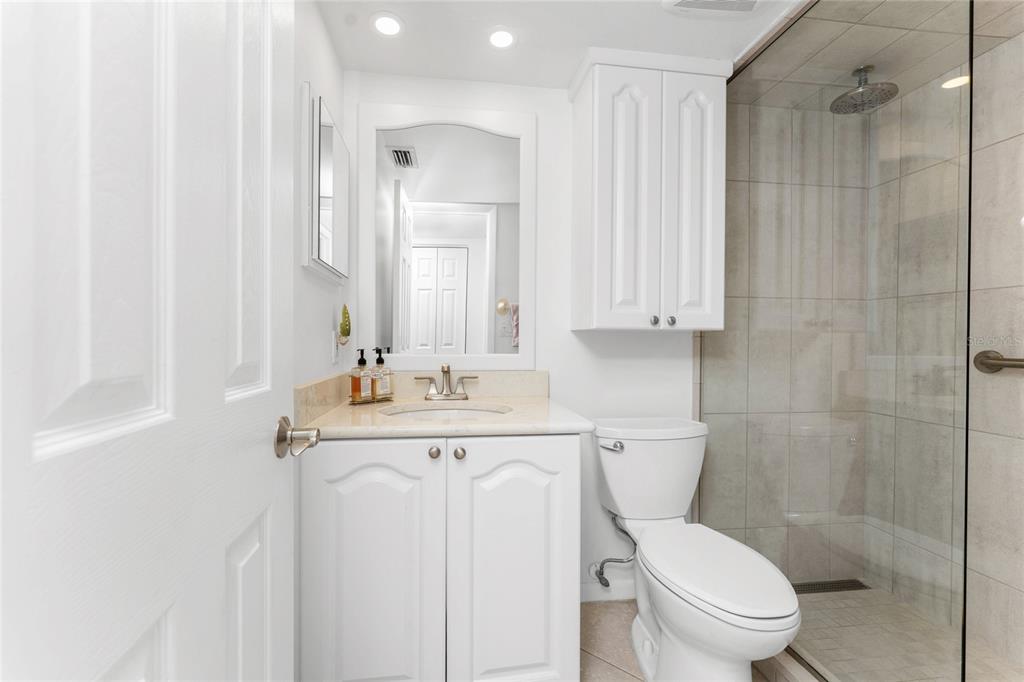 1551 Beach Road, Unit 204 Englewood, FL 34223 - Photo 23 of 55 a bathroom with a toilet a sink a mirror a vanity and shower