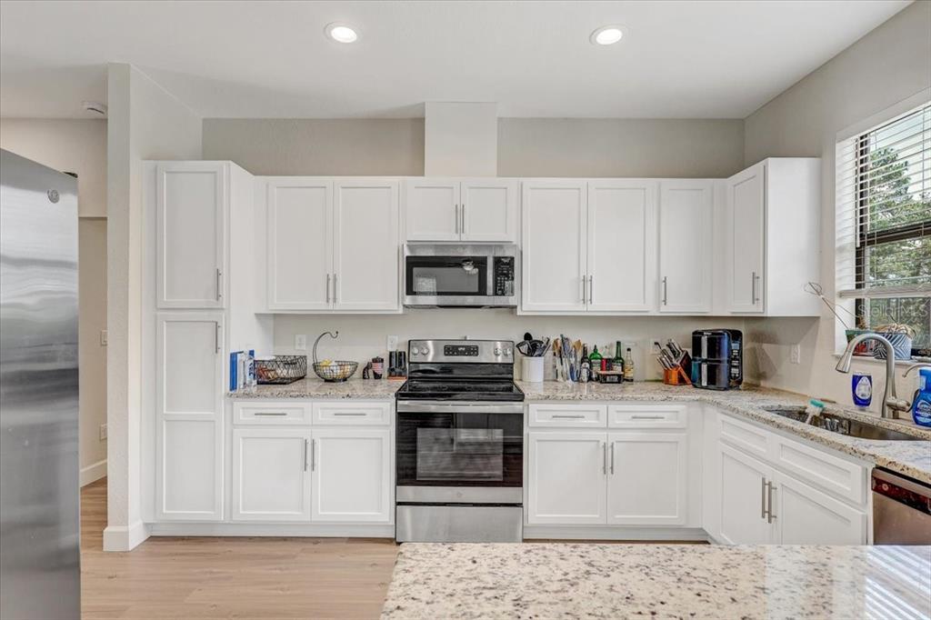 7314 Madrid Road Weeki Wachee, FL 34613 - Photo 14 of 54 a kitchen with white cabinets and appliances