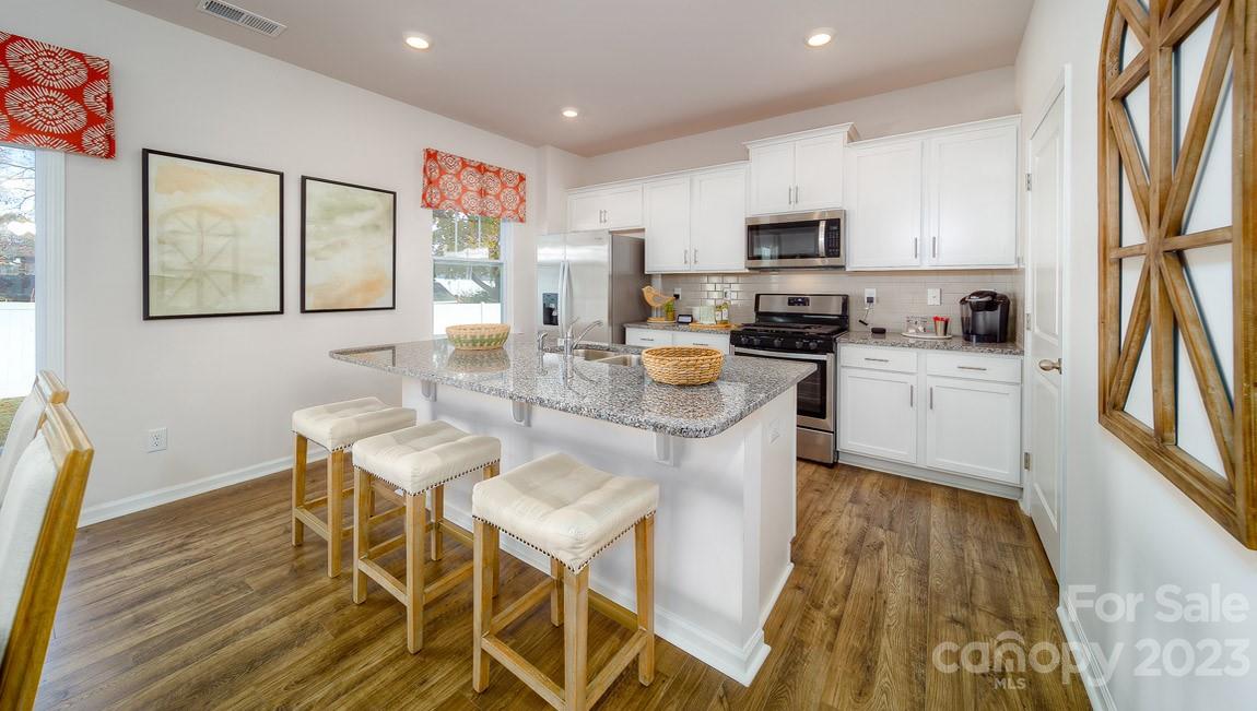 111 Wheatfield Road Fletcher, NC 28732 - Photo 6 of 36 a kitchen with stainless steel appliances granite countertop a stove top oven a sink a dining table and chairs with wooden floor