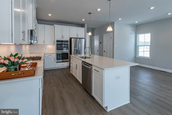 a kitchen with stainless steel appliances kitchen island granite countertop a stove a sink and a refrigerator