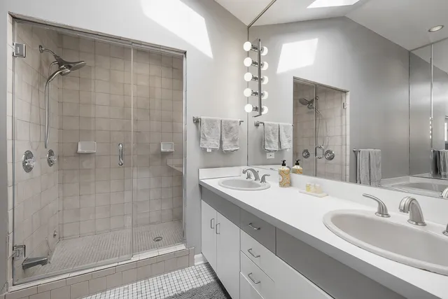 a bathroom with a double vanity sink mirror and shower