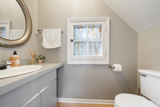 a bathroom with a toilet sink a mirror and a window