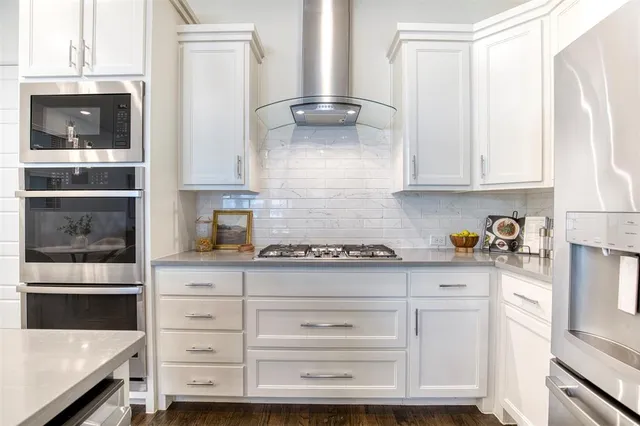 a kitchen with granite countertop white cabinets and stainless steel appliances