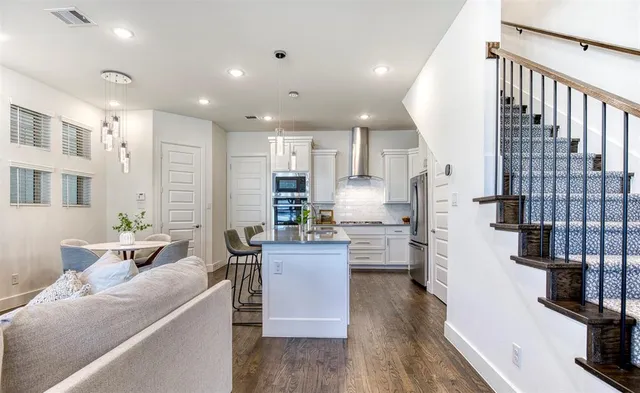 a living room with stainless steel appliances kitchen island granite countertop furniture a rug a kitchen and a sink