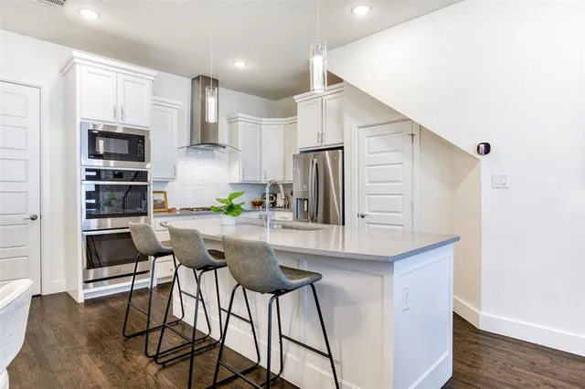 a kitchen with stainless steel appliances a dining table chairs refrigerator and cabinets