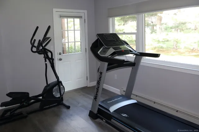 a room with gym equipment on wooden floor and windows