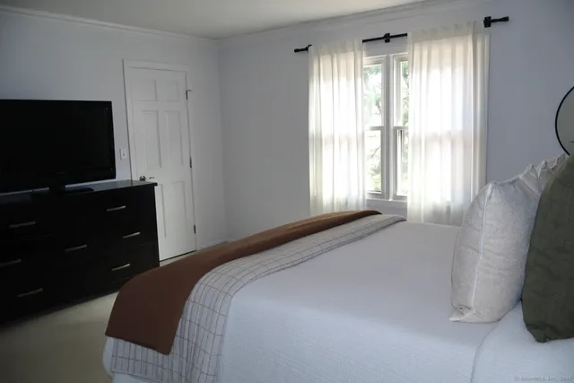 a bedroom with a bed and a flat tv screen on dresser