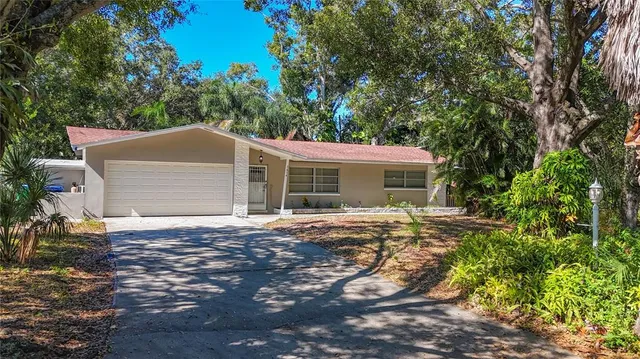 a view of a house with a yard and large tree