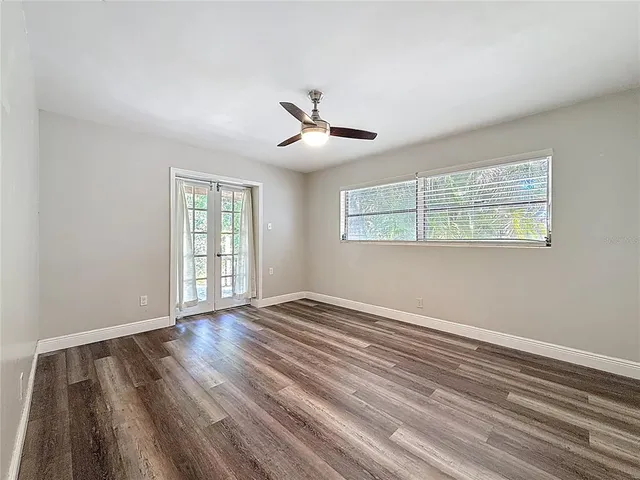 a view of empty room with wooden floor and fan