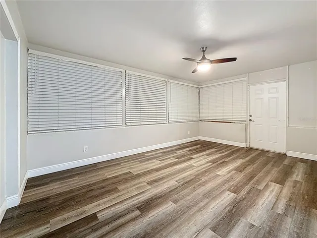 a view of empty room with wooden floor and fan