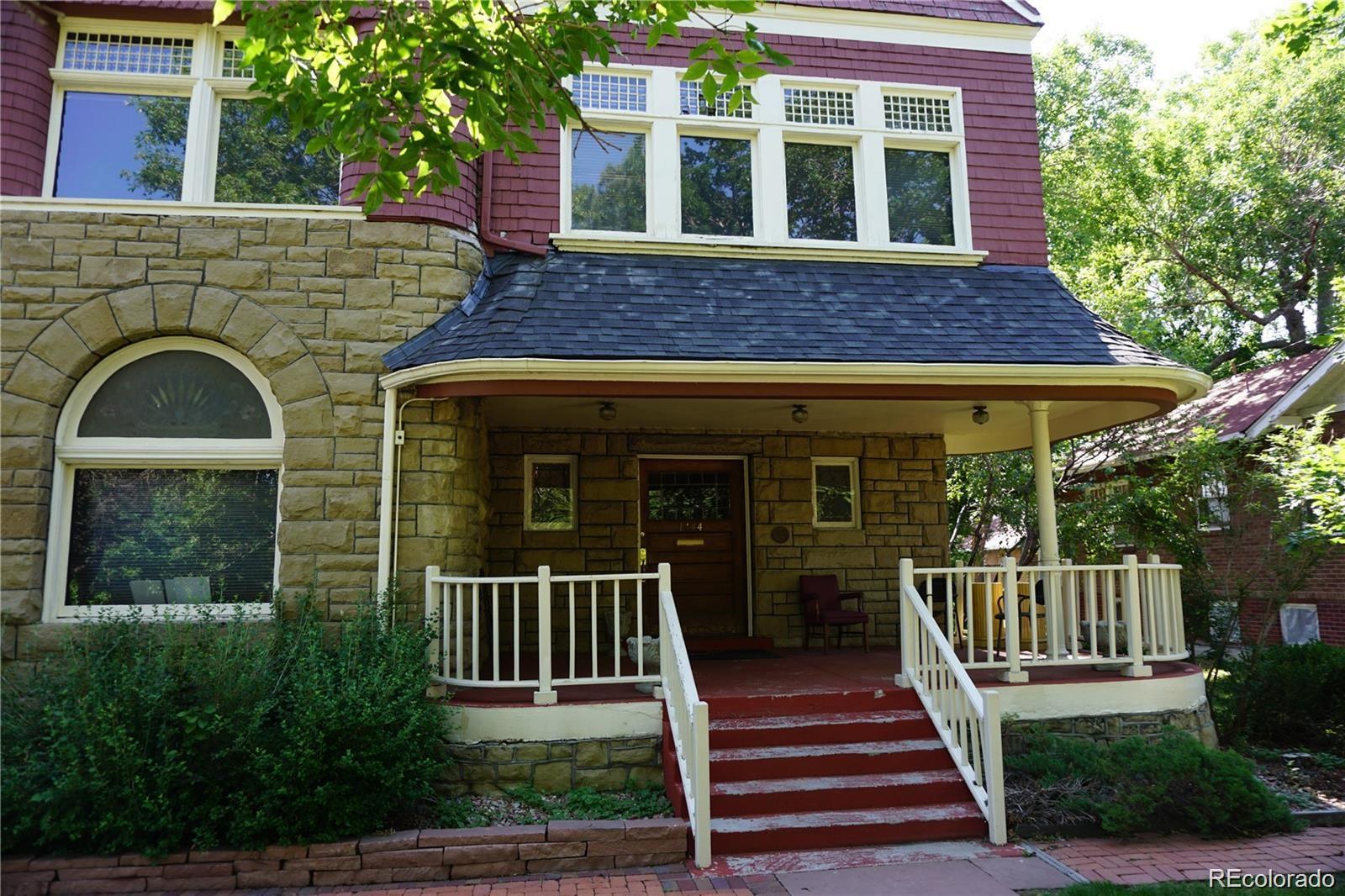 1444 Stuart Street Denver, CO 80204 - Photo 3 of 23 a view of a brick house with large windows and a table and chairs