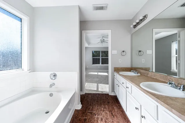 a bathroom with a granite countertop tub sink and mirror