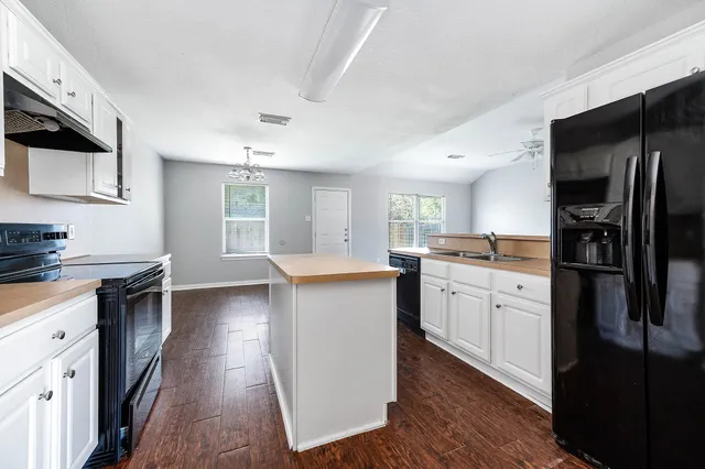 a kitchen with granite countertop a refrigerator stove top oven and sink