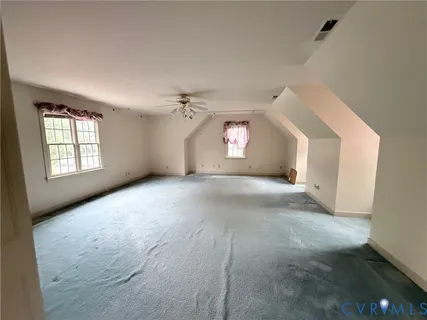 an empty room with windows and chandelier fan