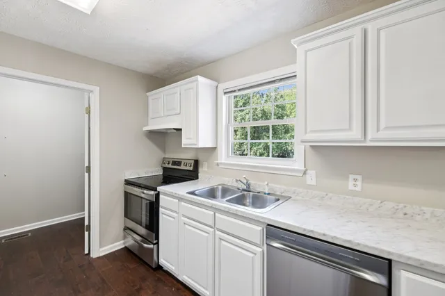 a kitchen with stainless steel appliances granite countertop white cabinets and a sink
