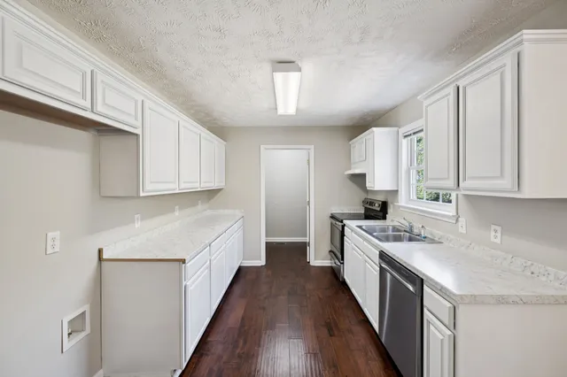 a kitchen with white cabinets sink and stove