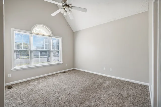 an empty room with chandelier fan and closet area