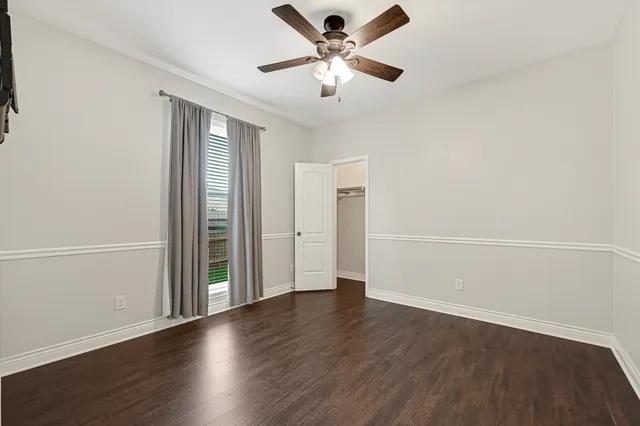 a view of an empty room with wooden floor fireplace and a window