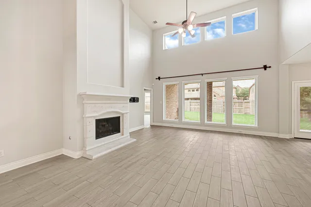 a view of an empty room and kitchen view with wooden floor