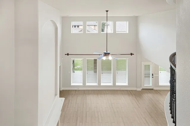 an empty room with ceiling fan and windows